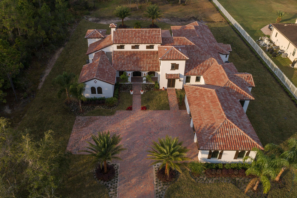 Стильный дизайн: большой, одноэтажный, белый частный загородный дом в средиземноморском стиле с облицовкой из цементной штукатурки и черепичной крышей - последний тренд