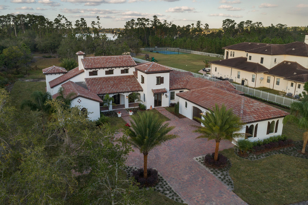 Example of a large tuscan white one-story stucco house exterior design in Orlando with a tile roof