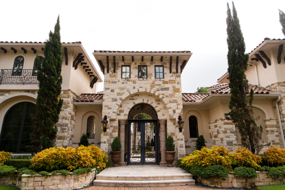 Huge tuscan multicolored two-story mixed siding house exterior photo in Houston with a hip roof and a tile roof