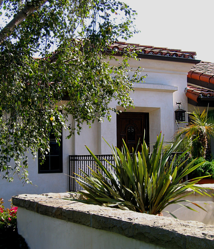 Exemple d'une façade de maison blanche méditerranéenne en stuc à un étage et de taille moyenne avec un toit à quatre pans et un toit en tuile.