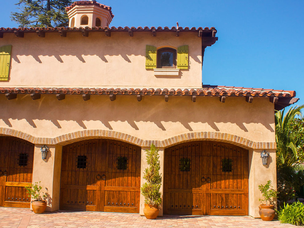 Ejemplo de fachada de casa beige mediterránea grande de dos plantas con revestimiento de adobe, tejado a dos aguas y tejado de teja de madera