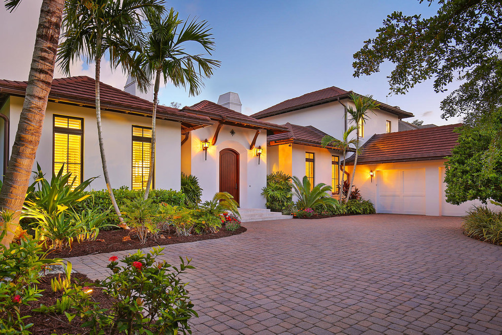 Example of a large island style white two-story stucco exterior home design in Tampa with a hip roof
