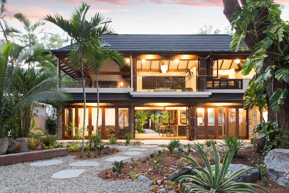 Imagen de fachada de casa marrón tropical de dos plantas con tejado a cuatro aguas y tejado de teja de barro