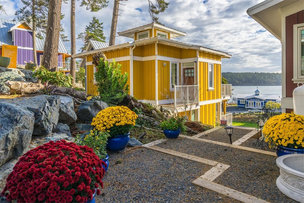 Kleines, Zweistöckiges Klassisches Einfamilienhaus mit Faserzement-Fassade, gelber Fassadenfarbe, Walmdach und Blechdach in Vancouver