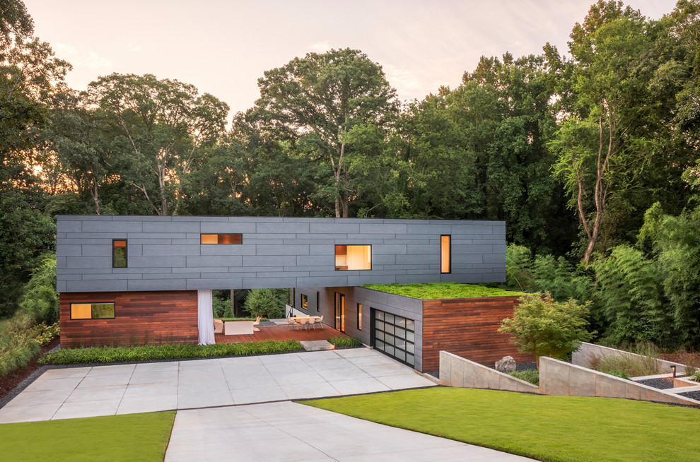 Cette image montre une grande façade de maison grise minimaliste à un étage avec un revêtement mixte, un toit plat et un toit végétal.