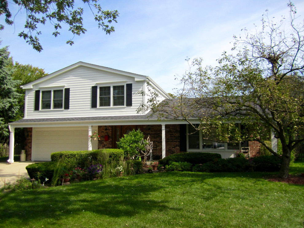Medium sized and white classic split-level house exterior in Chicago with mixed cladding.