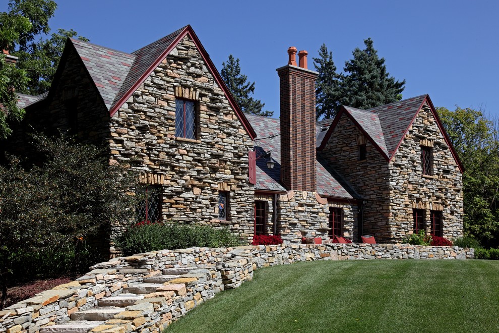 Пример оригинального дизайна: большой, двухэтажный частный загородный дом в классическом стиле с облицовкой из камня, двускатной крышей и крышей из гибкой черепицы