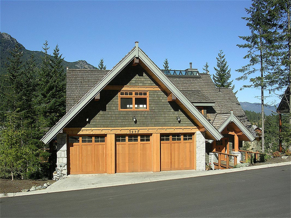 Large mountain style green three-story wood house exterior photo in Vancouver with a gambrel roof