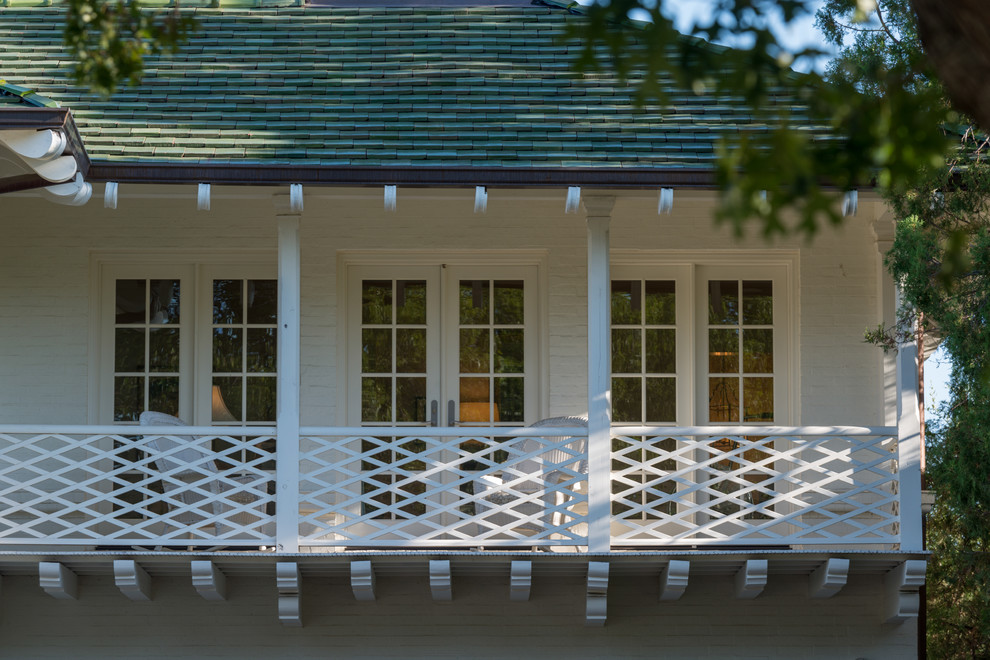 Modelo de fachada de casa blanca bohemia de tamaño medio de dos plantas con revestimiento de ladrillo, tejado a cuatro aguas y tejado de teja de madera