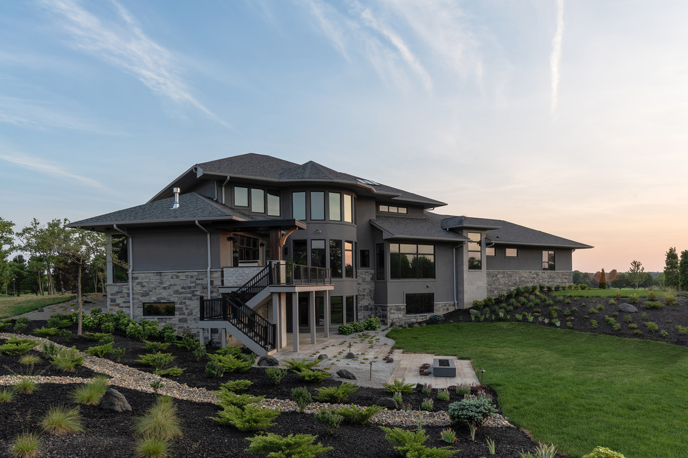 Пример оригинального дизайна: большой, двухэтажный, серый частный загородный дом в стиле модернизм с облицовкой из камня, вальмовой крышей и крышей из гибкой черепицы