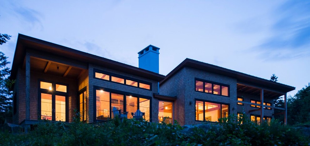 Immagine della facciata di una casa grande marrone contemporanea a un piano con rivestimento in legno e tetto piano
