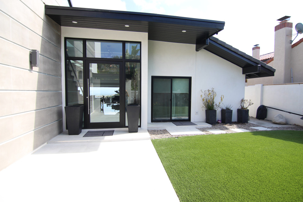 Ejemplo de fachada de casa multicolor minimalista grande de dos plantas con revestimiento de estuco, tejado plano y tejado de teja de barro