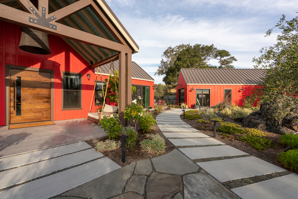 Idée de décoration pour une façade de maison rouge champêtre en bois de plain-pied avec un toit à deux pans et un toit en métal.