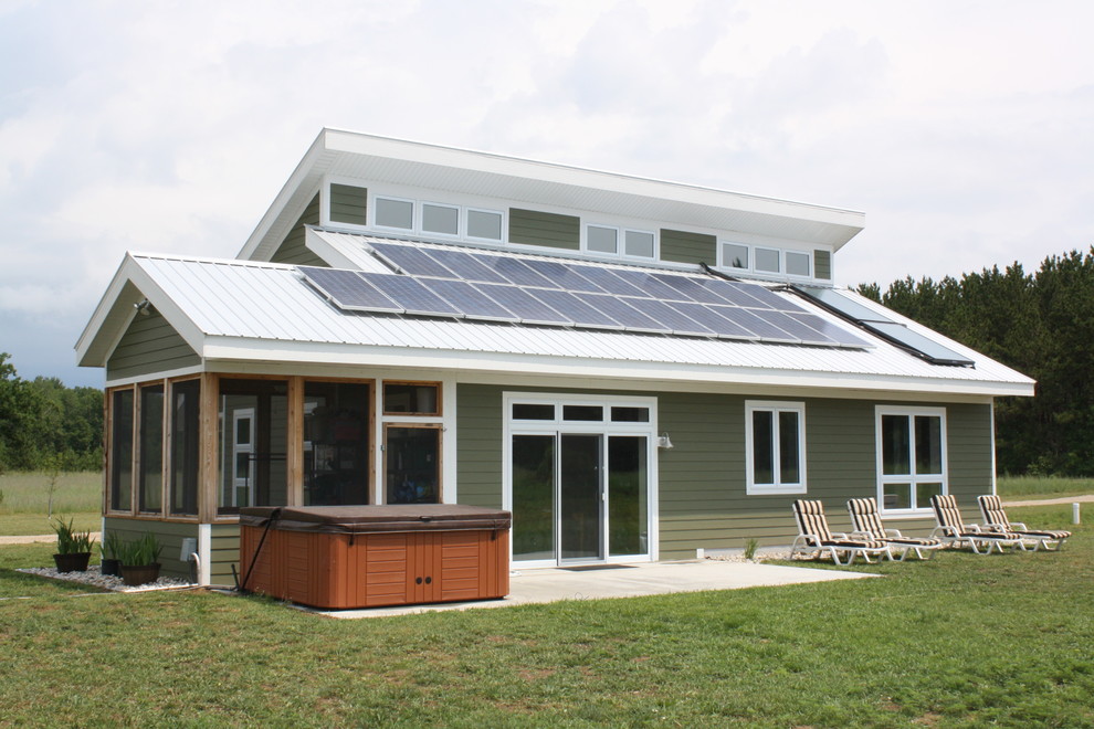 Exempel på ett litet modernt grönt hus, med två våningar, fiberplattor i betong, pulpettak och tak i metall