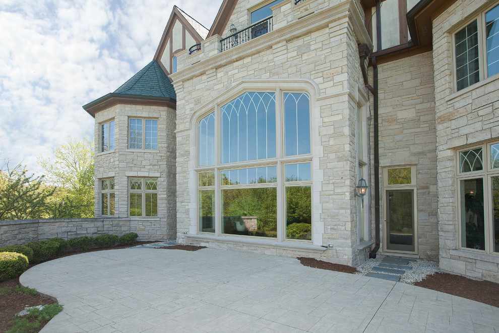 Large traditional beige three-story stone gable roof idea in Chicago
