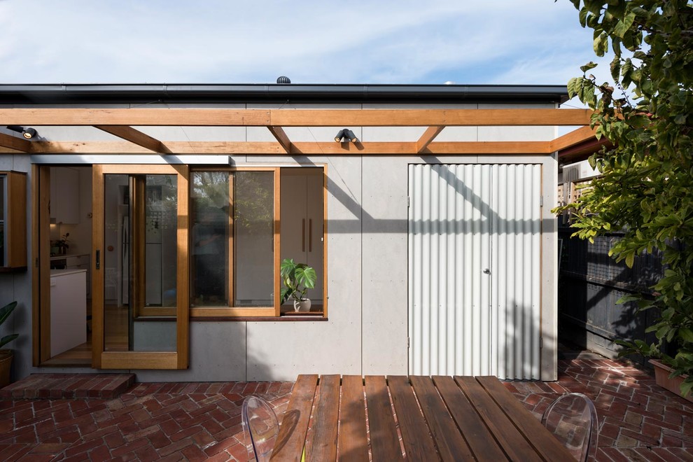 На фото: маленький, одноэтажный, серый частный загородный дом в скандинавском стиле с облицовкой из бетона, вальмовой крышей и металлической крышей для на участке и в саду