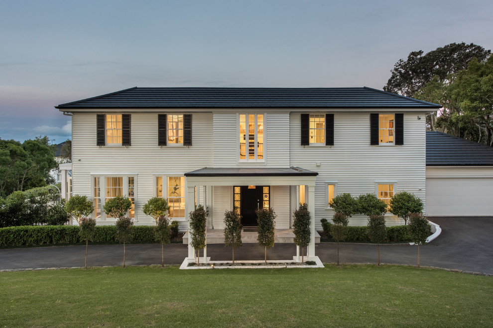 Large and white traditional detached house in Auckland with three floors, wood cladding, a hip roof and a shingle roof.