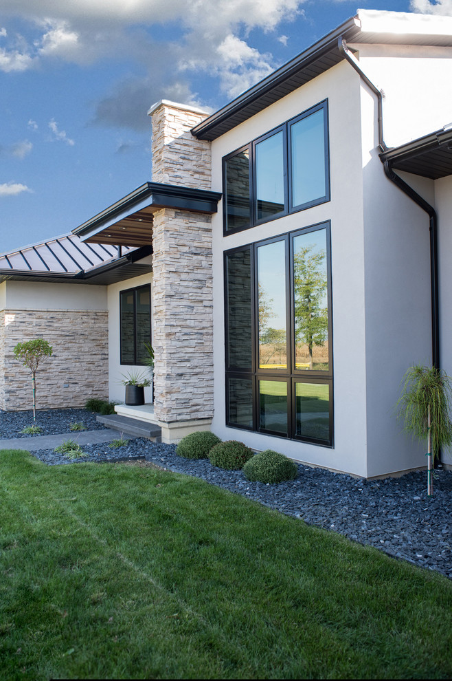 Modelo de fachada de casa beige minimalista de tamaño medio de dos plantas con revestimiento de estuco, tejado a cuatro aguas y tejado de metal