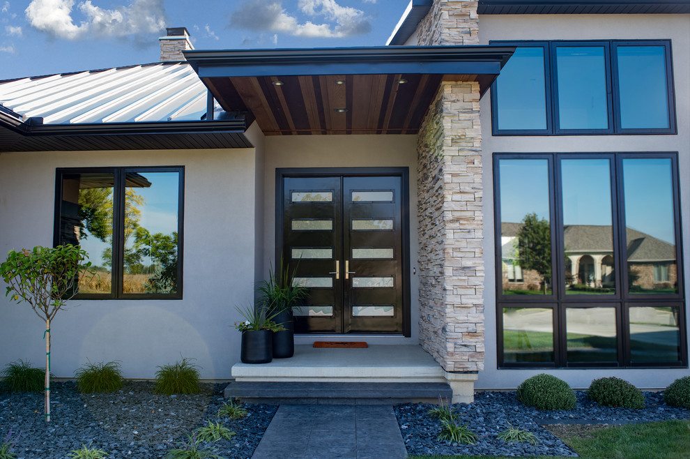 Réalisation d'une façade de maison beige minimaliste en stuc de taille moyenne et à un étage avec un toit à quatre pans et un toit en métal.