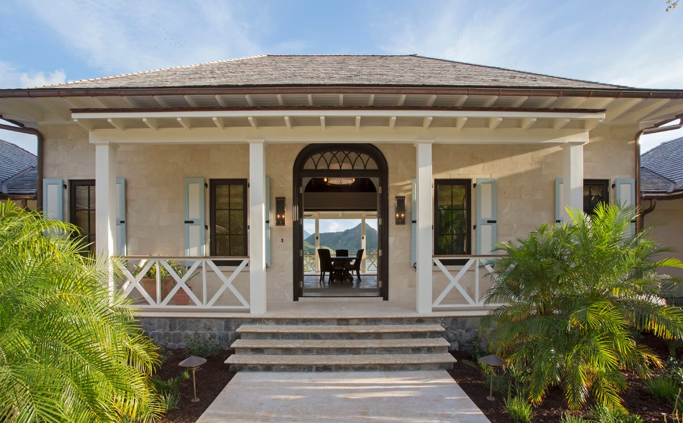 Ispirazione per la facciata di una casa beige tropicale a due piani con rivestimento in pietra e tetto a padiglione