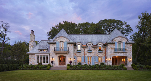 front view of french country home with light stonewalls and blue windows