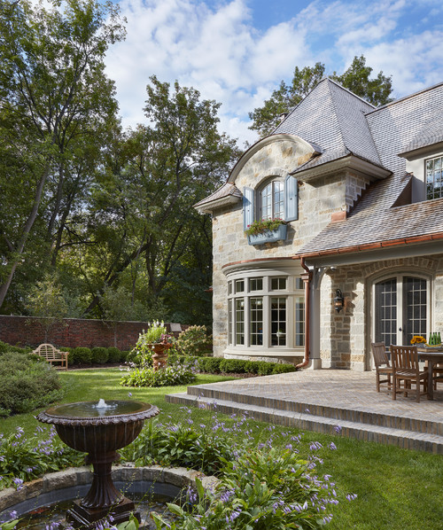 Garden with stone fountains and French country home with french windows