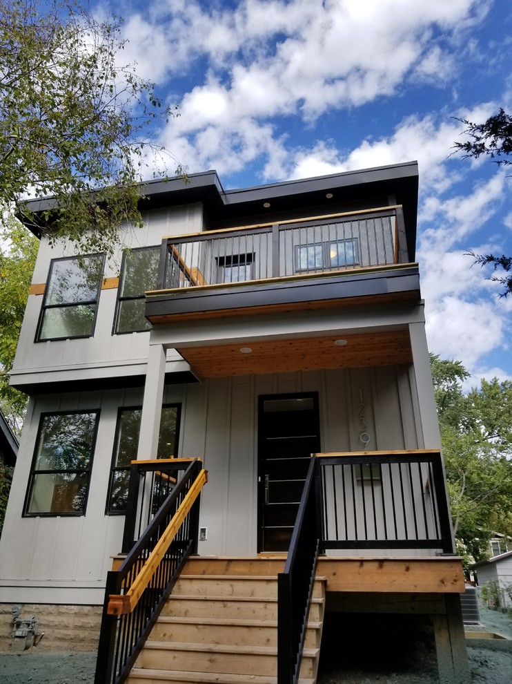Diseño de fachada de casa gris actual de tamaño medio de dos plantas con revestimiento de aglomerado de cemento y tejado plano