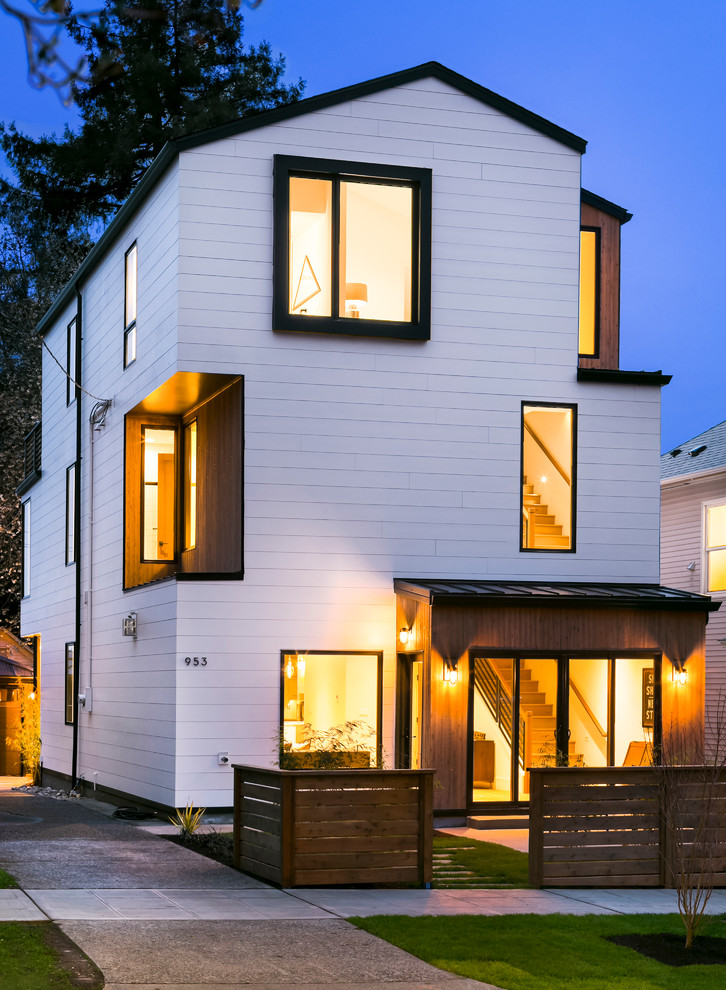 Diseño de fachada de casa blanca actual de tres plantas con revestimiento de madera y tejado a dos aguas