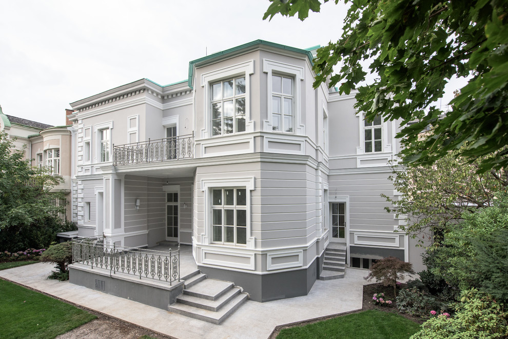 На фото: двухэтажный, серый частный загородный дом среднего размера в викторианском стиле с облицовкой из цементной штукатурки и металлической крышей с