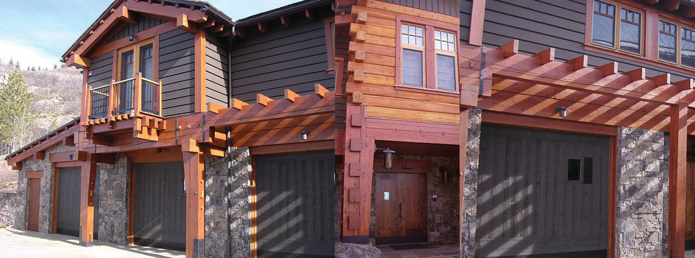 Foto della facciata di una casa grande marrone rustica a tre piani con rivestimento in legno e tetto a capanna