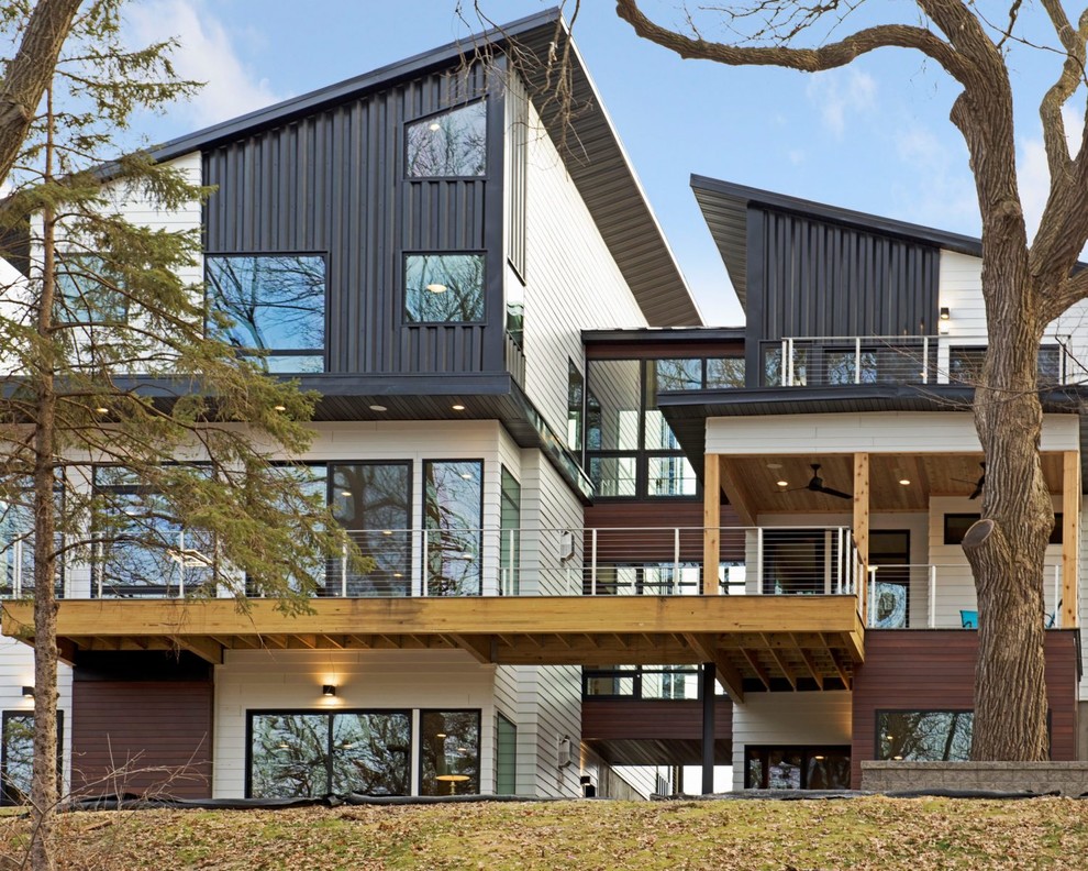 Diseño de fachada de casa blanca actual grande a niveles con revestimientos combinados y tejado de un solo tendido