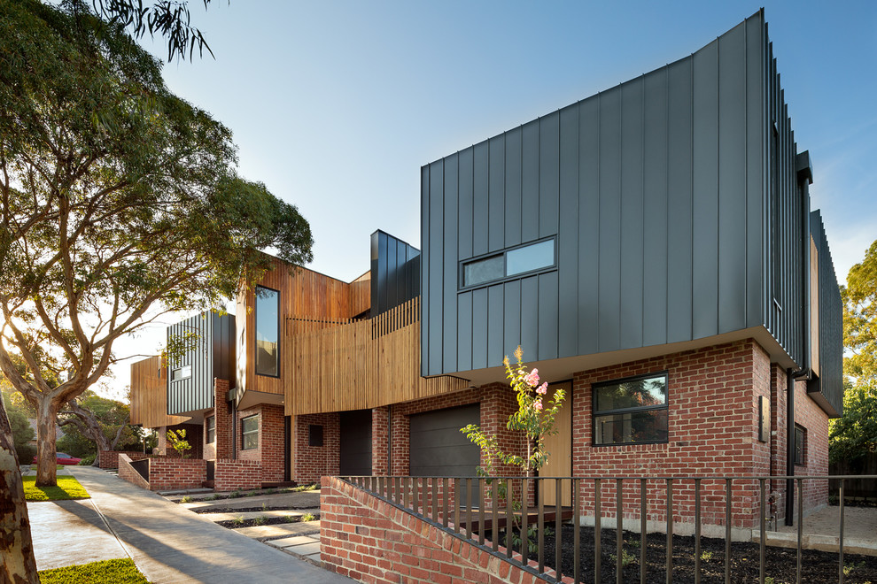 This is an example of a medium sized and black contemporary two floor house exterior in Melbourne with metal cladding and a flat roof.