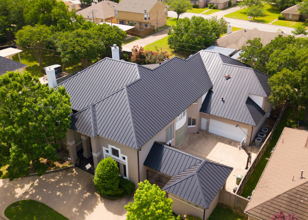 Example of a large beige two-story house exterior design in Dallas with a metal roof