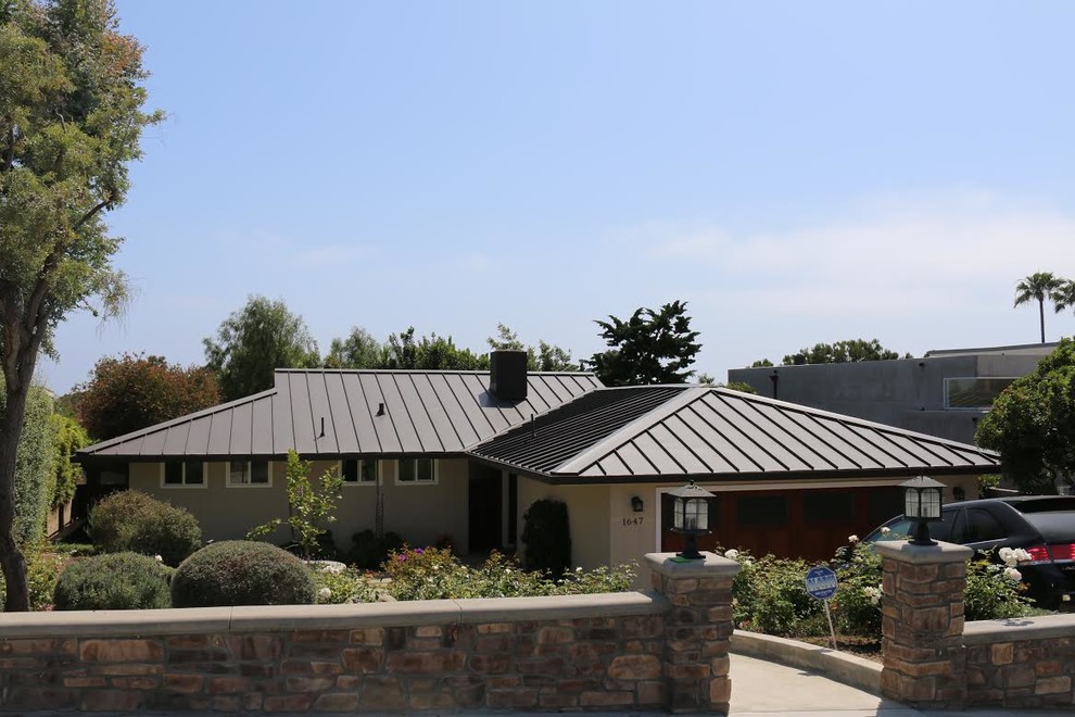 Aménagement d'une façade de maison beige bord de mer en stuc de taille moyenne et de plain-pied avec un toit à deux pans et un toit en métal.