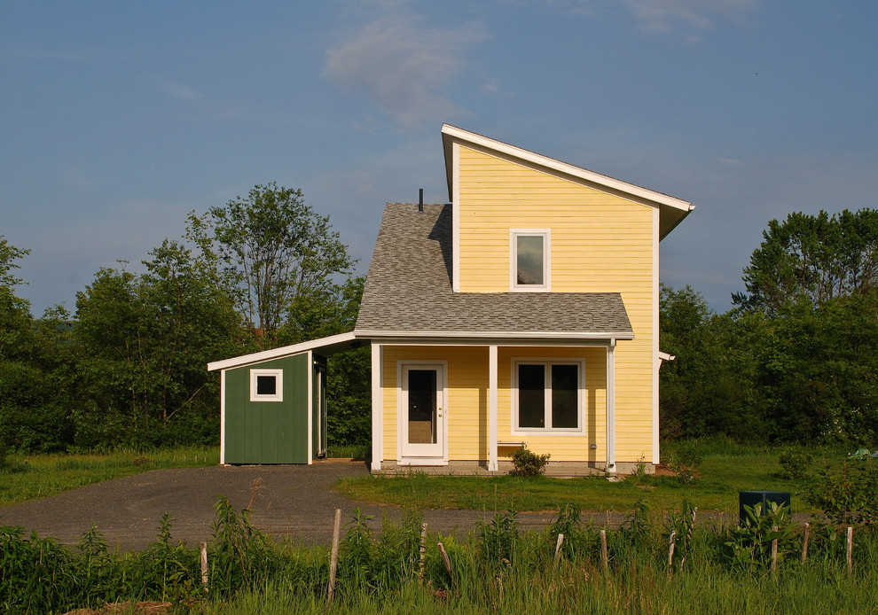 Foto della facciata di una casa gialla country a due piani con rivestimento in legno