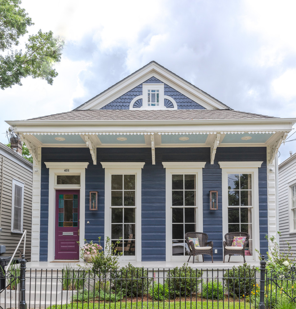 This is an example of a blue and small classic bungalow detached house in New Orleans with wood cladding, a mansard roof and a shingle roof.