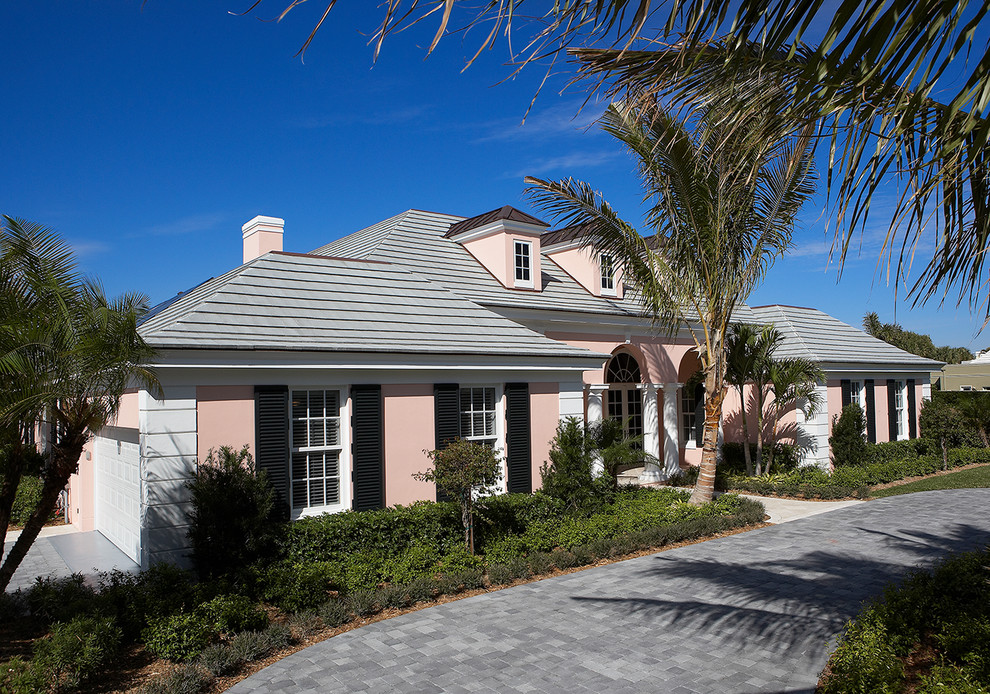This is an example of a medium sized mediterranean two floor render detached house in Miami with a hip roof, a shingle roof and a pink house.