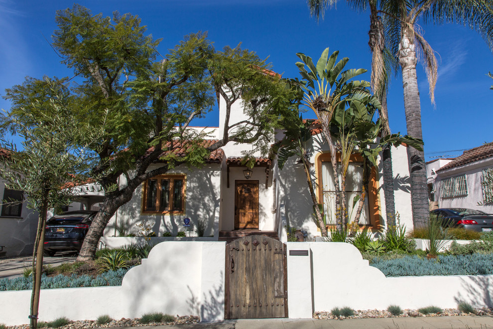 Diseño de fachada de casa blanca mediterránea grande de dos plantas con revestimiento de estuco, tejado a dos aguas y tejado de teja de barro