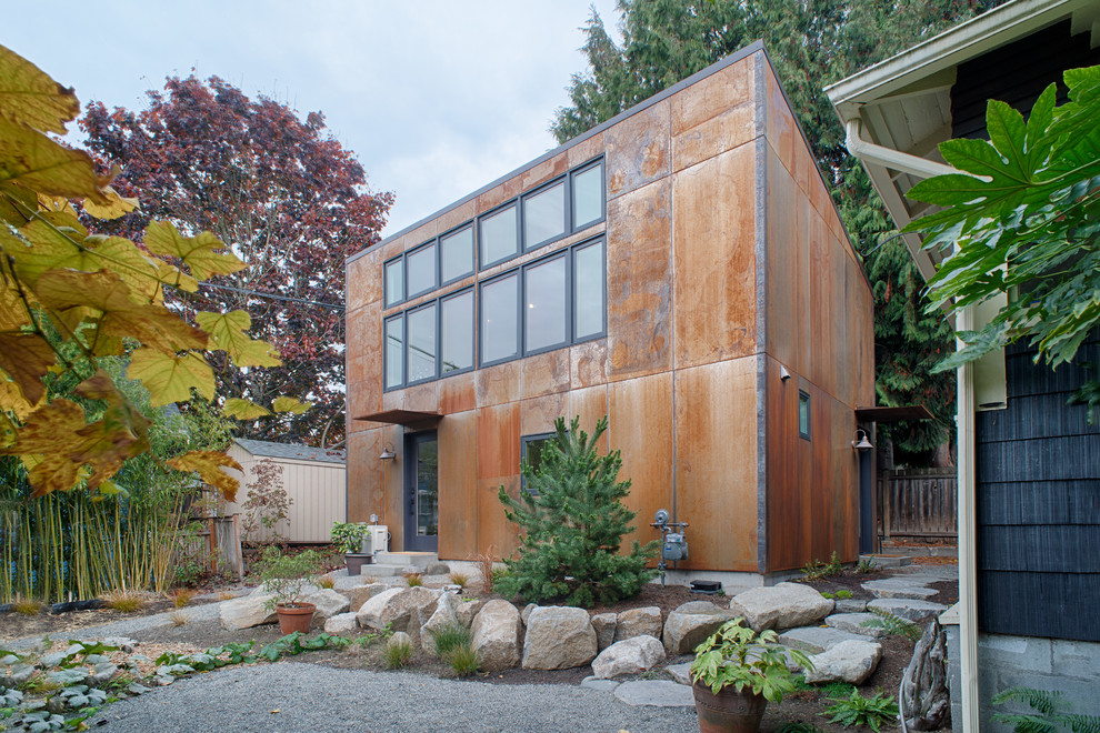 На фото: маленький, двухэтажный, коричневый частный загородный дом в стиле лофт с облицовкой из металла и односкатной крышей для на участке и в саду с