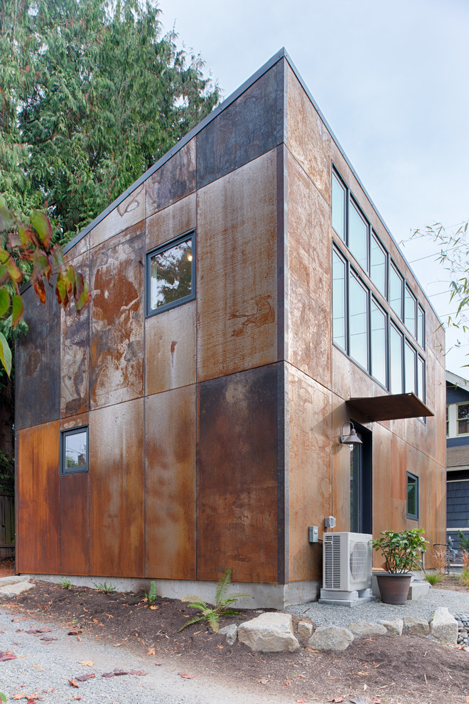Cette photo montre une petite façade de maison métallique et marron moderne à un étage avec un toit en appentis et un toit en métal.