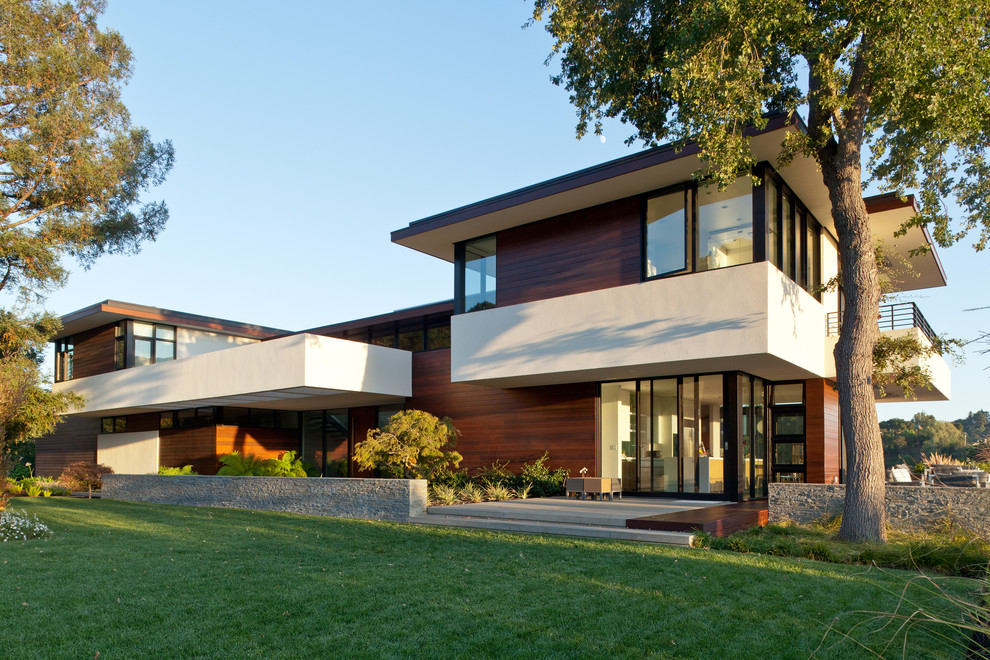 Esempio della facciata di una casa grande moderna a due piani con rivestimento in legno e tetto piano