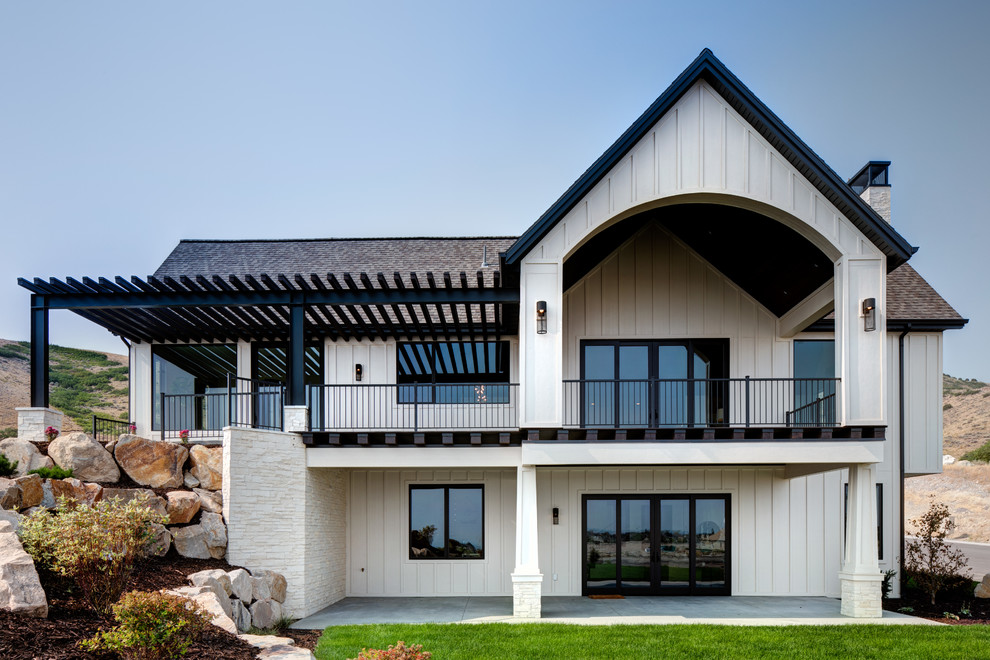Diseño de fachada de casa beige actual grande de dos plantas con revestimiento de aglomerado de cemento, tejado a dos aguas y tejado de varios materiales