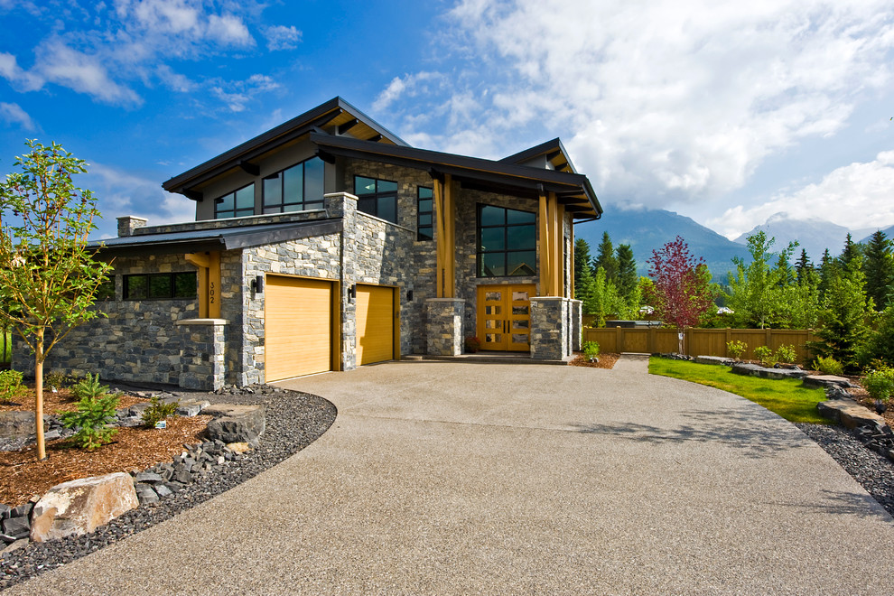 This is an example of a gey rustic house exterior in Calgary with stone cladding and a lean-to roof.