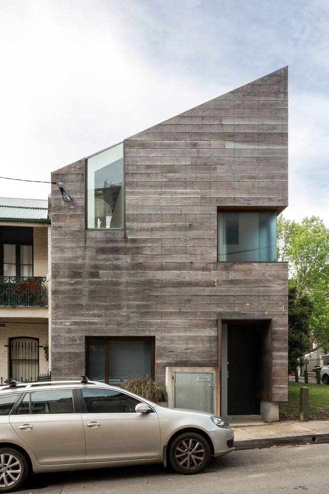 This is an example of a small and gey contemporary house exterior in Sydney with three floors and wood cladding.