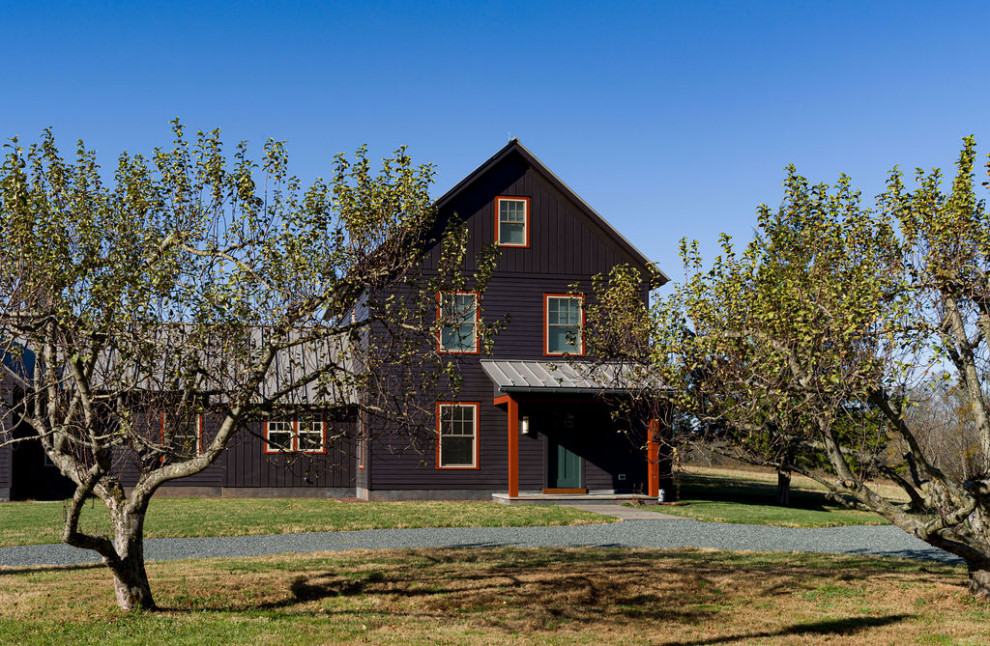 Immagine della villa grande nera country a tre piani con rivestimento con lastre in cemento e copertura in metallo o lamiera
