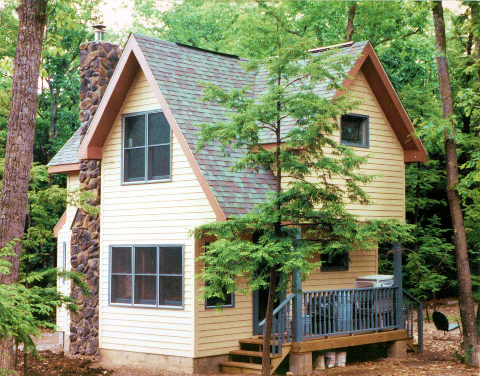 Пример оригинального дизайна: маленький, двухэтажный, деревянный, желтый дом в стиле кантри для на участке и в саду