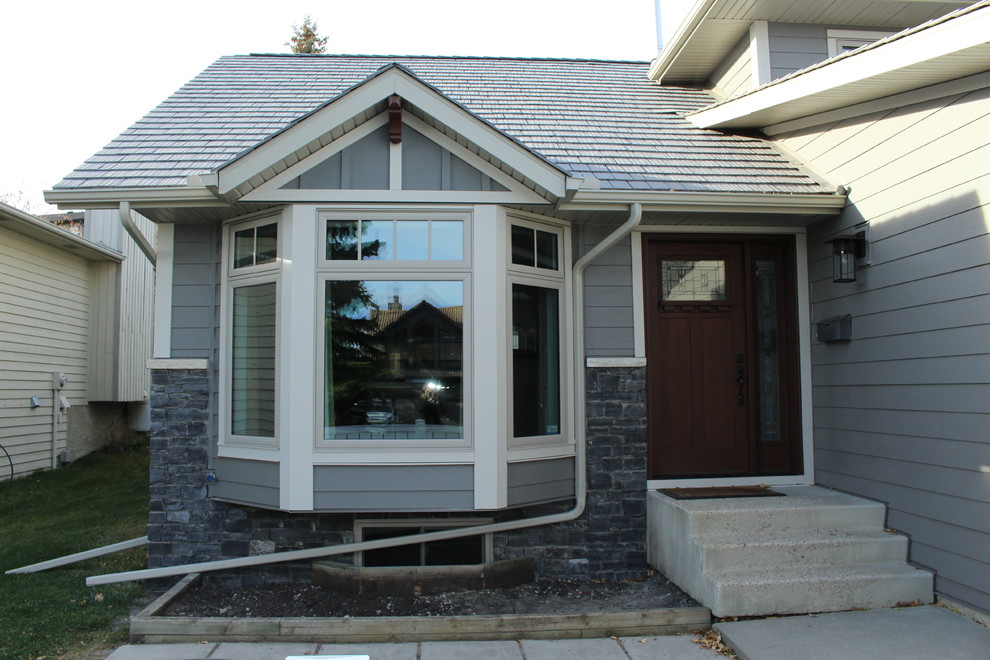 Large and gey classic split-level detached house in Calgary with concrete fibreboard cladding.