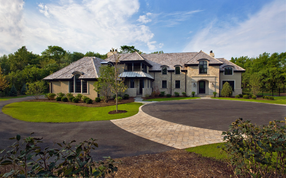 На фото: большой, двухэтажный, бежевый дом в классическом стиле с облицовкой из цементной штукатурки и вальмовой крышей