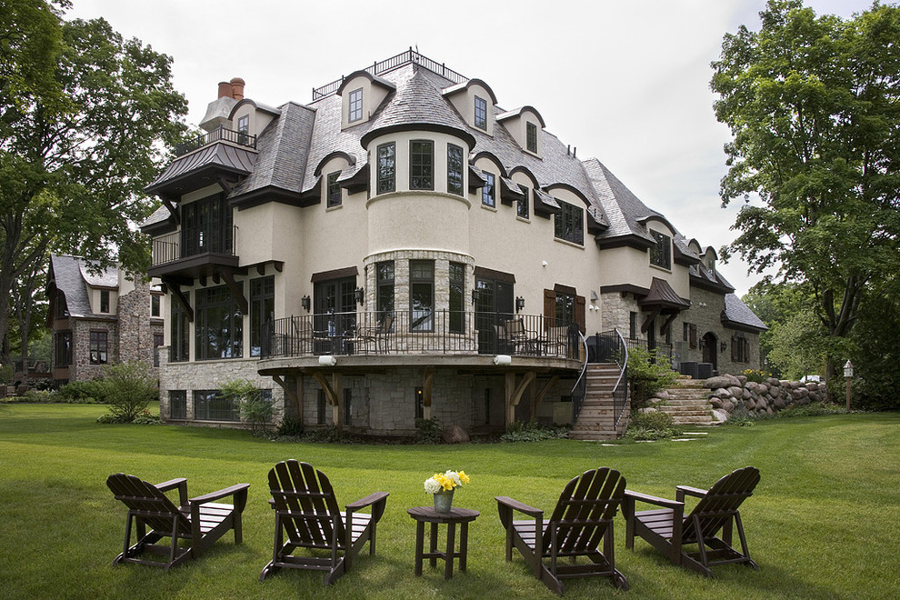 Пример оригинального дизайна: огромный, трехэтажный, бежевый дом в классическом стиле с вальмовой крышей и комбинированной облицовкой