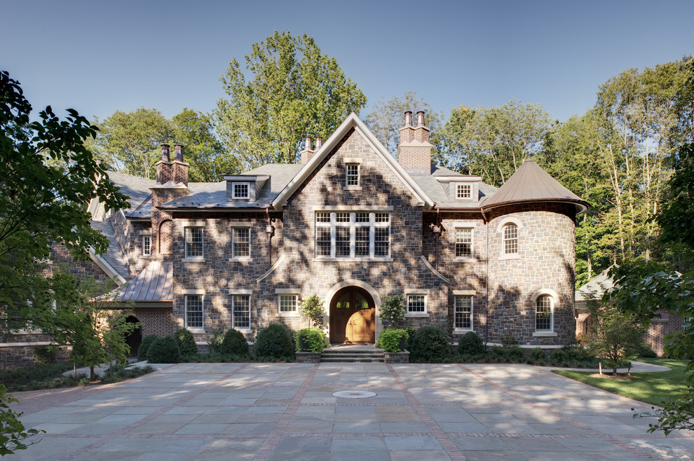 Large and brown traditional house exterior in New York with three floors, a pitched roof and stone cladding.